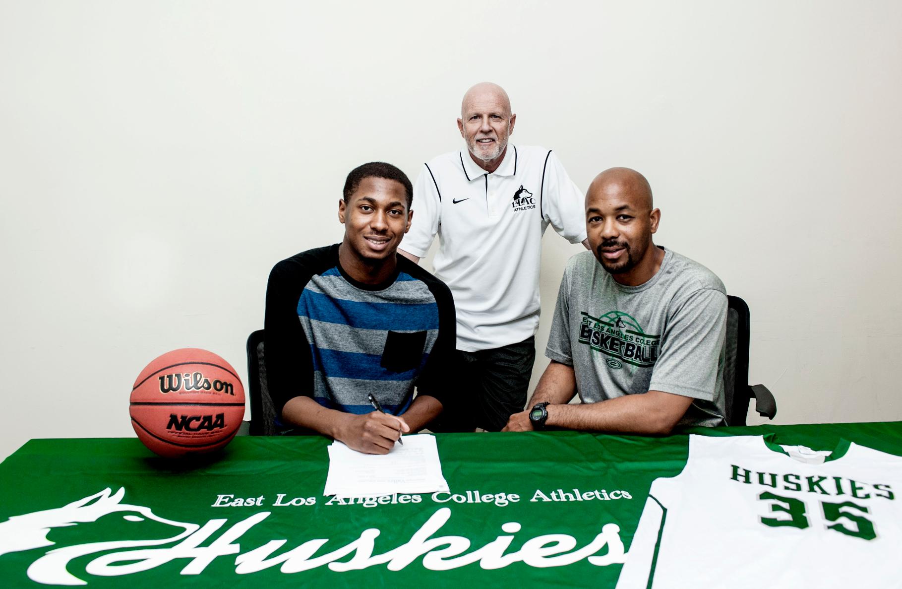 East Los Angeles College sophomore Arinze Anakwenze signs a scholarship agreement and a National Letter of Intent with Mississippi Valley State University next to Athletic Director Al Cone and Head Basketball Coach John Mosley.